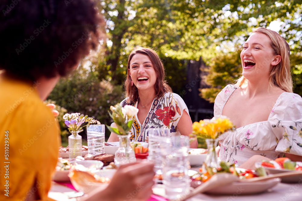 Three Female Friends Sitting Outdoors In Summer Garden At Home Eating Meal Together Three Female Friends Sitting Outdoors In Summer Garden At Home Eating Meal Together