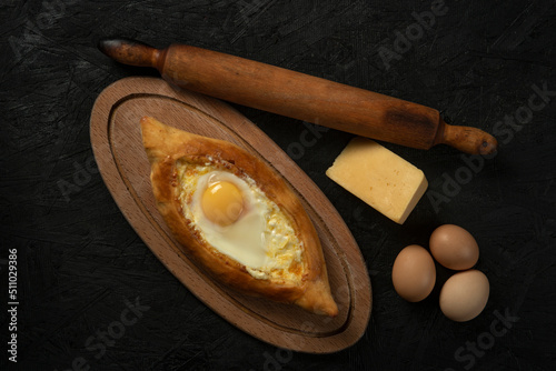 . Caucasian flatbread adjarian khachapuri with egg on a dark wooden . Adjarian Khachapuri Georgian cheese bread