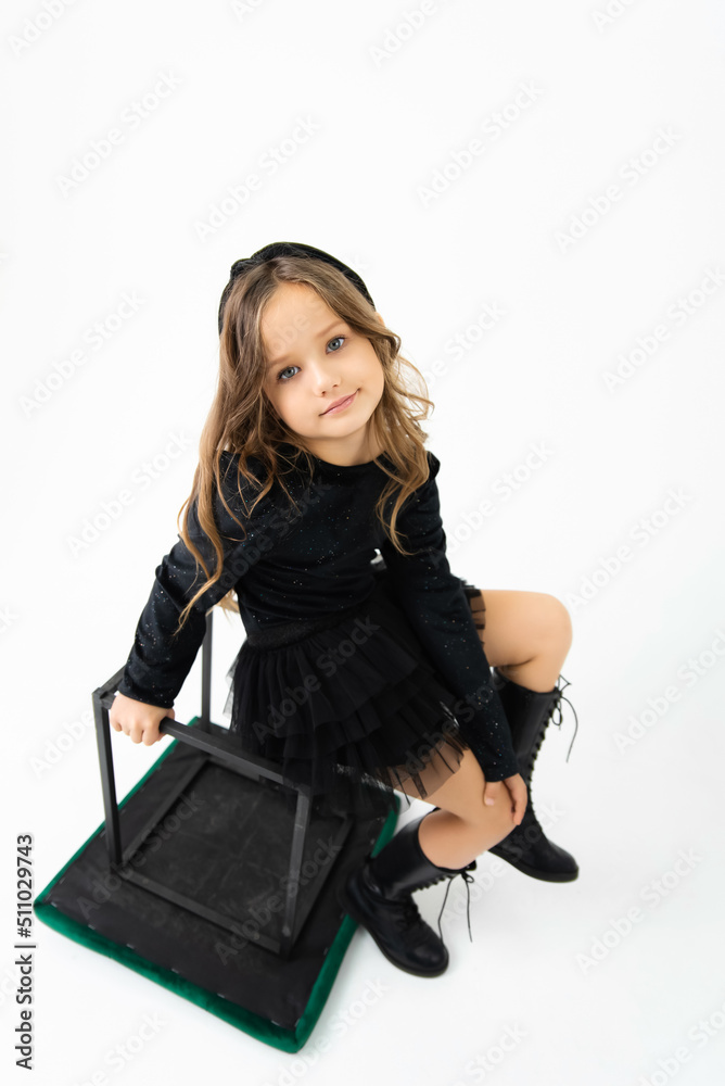 Fototapeta premium A girl in a black blouse and skirt is looking at the camera