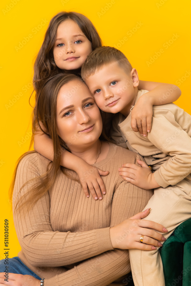 Caring mother with her children on a yellow background