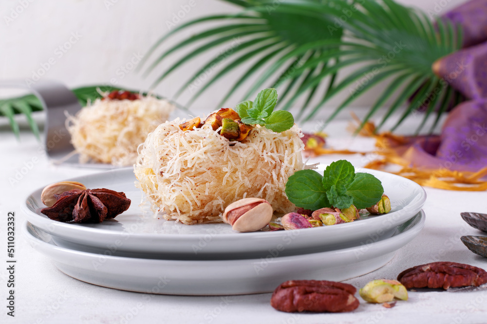 Kunafa dessert made of kataifi dough with pistachio and pecan nuts served on the plate. Egyptian cuisine