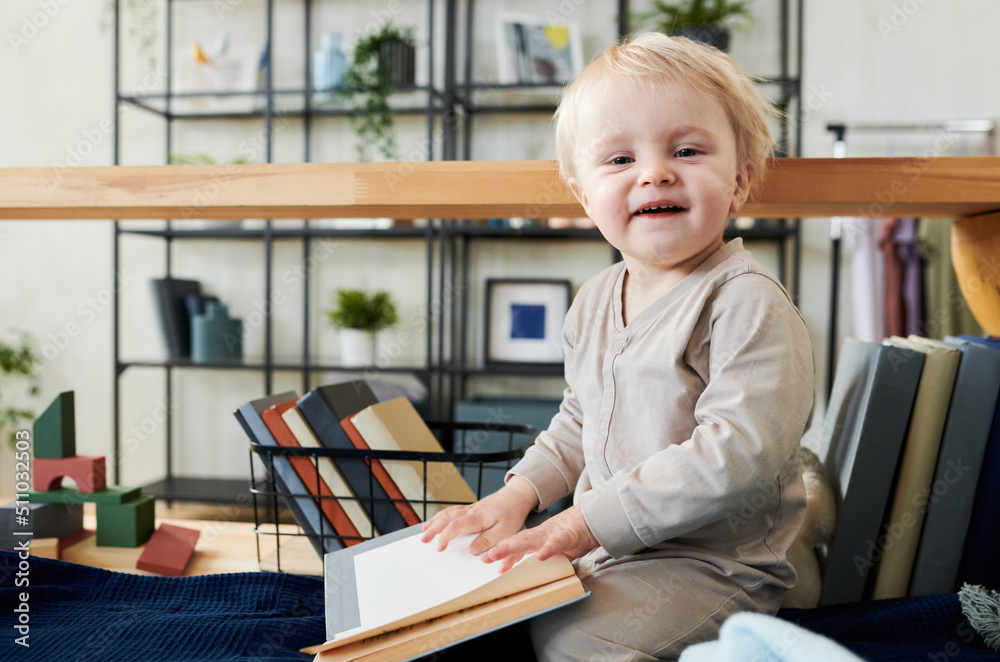 Portrait of adorable child looking at camera while sitting on bed and flipping through the pages of books Portrait of adorable child looking at camera while sitting on bed and flipping through the pages of books