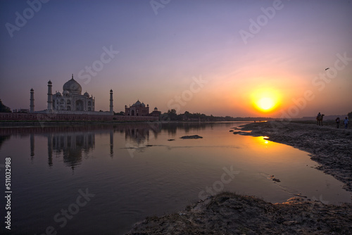 Taj Mahal seen from the river, with camel and tourists on the river bank.