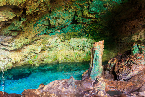 View of beautiful natural pool of crystal clear water formed in a rocky cave with stalagmites and stalagmites. Kuza cave in Zanzibar, Tanzania photo