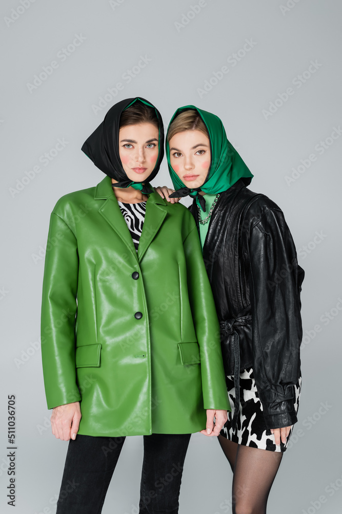 women in green and black jackets and kerchiefs looking at camera isolated on grey. women in green and black jackets and kerchiefs looking at camera isolated on grey.