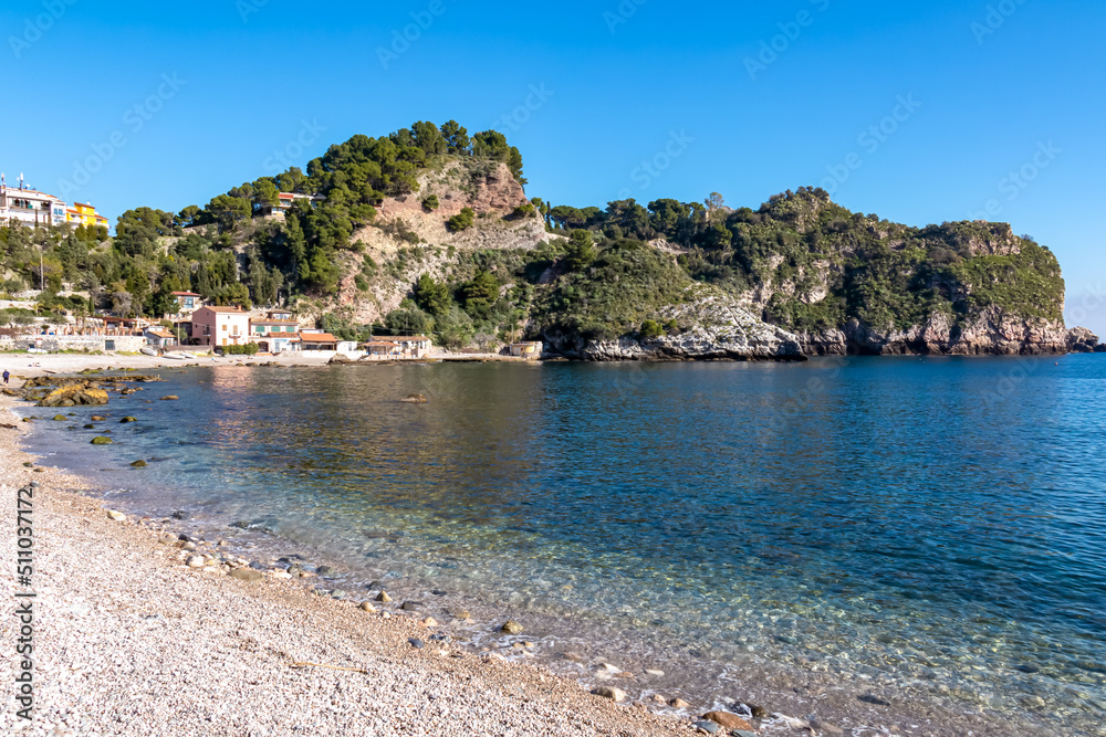 Panoramic view from beach Spiaggia di Isola Bella on paradise resort peninsula in Taormina, Sicily, Italy, Europe, EU. Paradise landscape at Mediterranean sea. Calm turquoise water surface Ionian sea