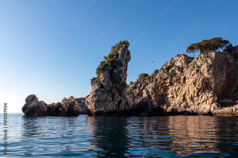 Touristic boat tour with panoramic view from open sea on the Mediterranean coastline near Isola Bella in Taormina, Sicily, Italy, Europe, EU. Coastal rock formations at Ionian Mediterranean sea