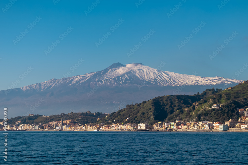 Touristic boat tour with panoramic view from open sea on snow capped volcano Mount Etna and the Ionian Mediterranean coastline near Isola Bella in Taormina, Sicily, Italy, Europe, EU. Rock formations