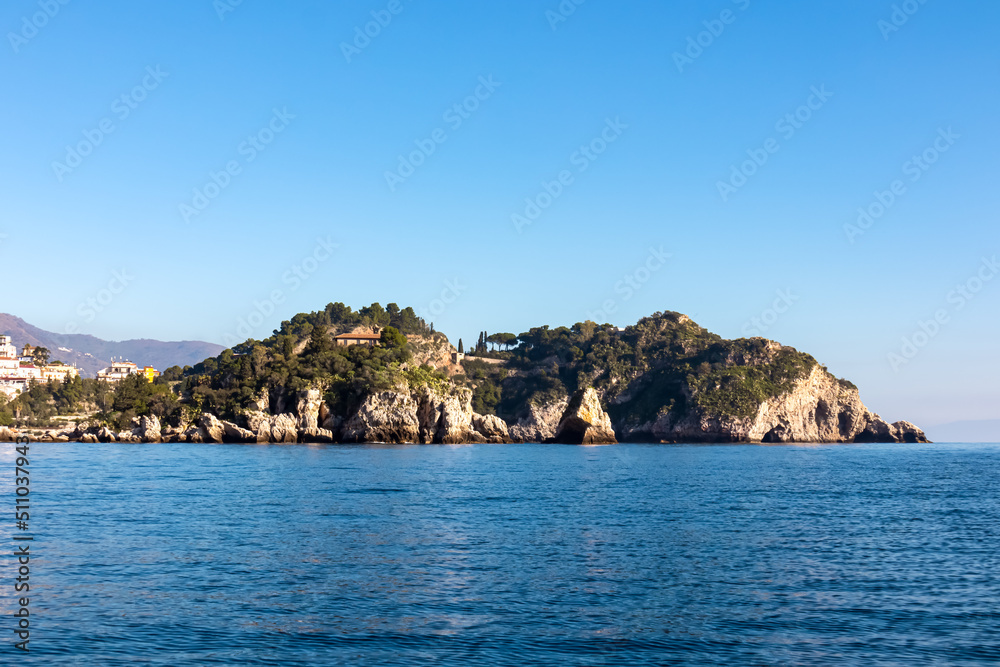 Panoramic view from the tourist island Isola Bella on the entrance of Blue Grotto (Grotta Azzurra) at Mediterranean coastline in Taormina, Sicily, Italy, Europe, EU. Calm water surface at Ionian sea