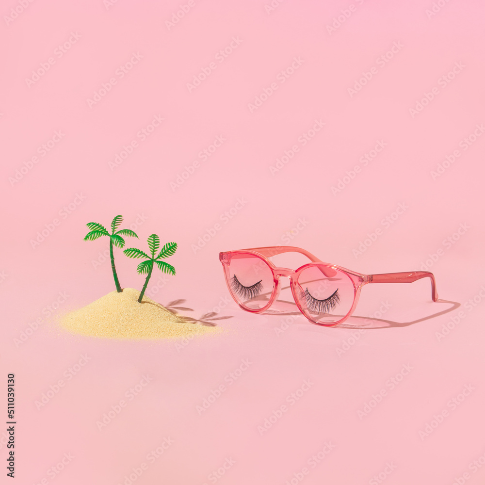 Summer holiday creative layout with plam tree figurines in sand and pink eyeglasses with false eyelashes on pastel pink background. 70s, 80s or 90s retro aesthetic fashion surreal concept. Summer holiday creative layout with plam tree figurines in sand and pink eyeglasses with false eyelashes on pastel pink background. 70s, 80s or 90s retro aesthetic fashion surreal concept.
