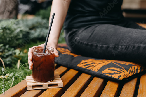 Foto Woman holding a glass jar with cold brew coffee outdoors.