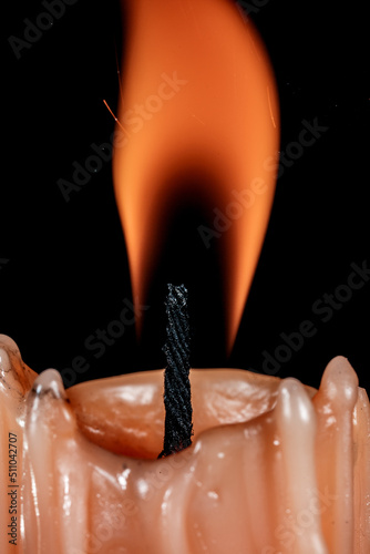 Burning candle. Yellow candle on a dark background close-up.