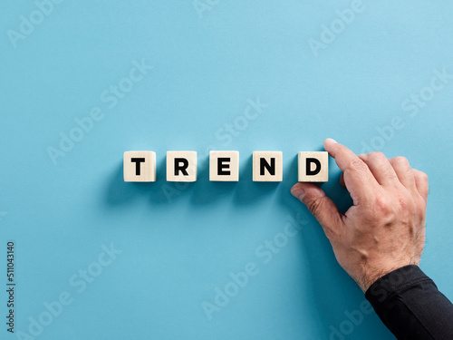 Male hand placing the wooden cubes with the word trend. New trends in business, technology or industry