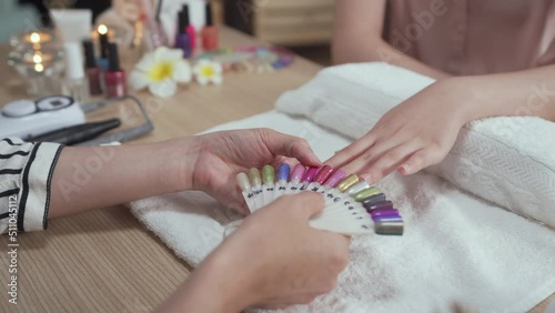 natural fingers touching colorful palette compare. close up female client hands choosing bright summer nail polish in beauty art salon. manicurist showing customer sample in manicure studio