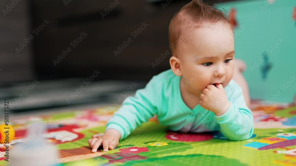 Sweet baby boy with funny hair lies on a mat. Adorable toddler interested with toys. Close up. Sweet baby boy with funny hair lies on a mat. Adorable toddler interested with toys. Close up.