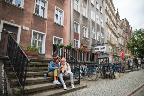 Happy senior couple tourists sitting on stairs and having take away coffee outdoors in town © Halfpoint