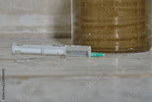 A filled syringe with an open needle lies on a table.