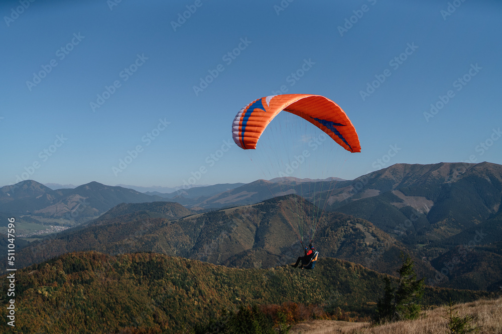 Paraglider flying in the blue sky with mountain in background. Paraglider flying in the blue sky with mountain in background.