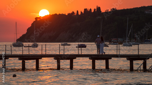 Sunset at the sea, people enjoying the sunlight at the pier