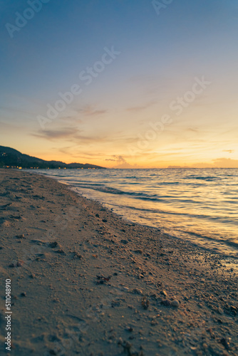 Sandy beach  surf and coastline at colorful sunset