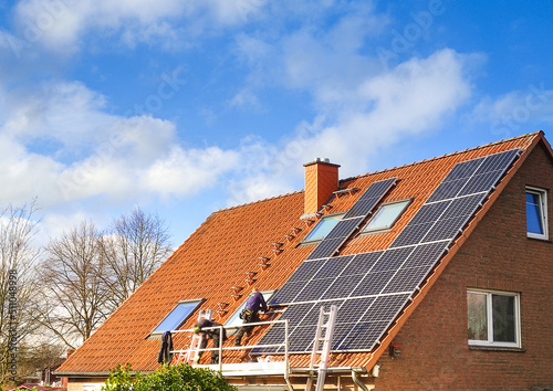 Handwerker installieren Photovoltaik Solar Anlage auf Einfamilienhaus bei Sonne   photo