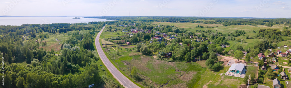 Aerial view of lake and small village. Village near the lake. Aerial view of the village and trees on the shore of lake.