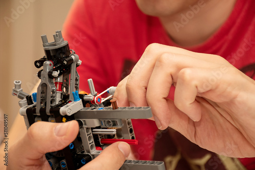 Hands holding piece of a machinery made from plastic construction kit parts details