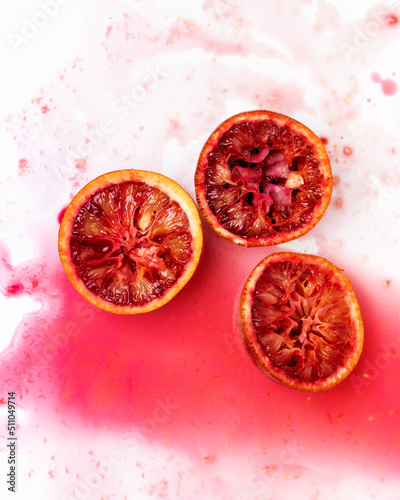 Squeezed Out Whole Ripe Juicy Sicilian Blood Oranges on White Background Orange Juice Spilled On Background Square