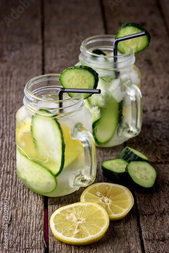 Glass Jar of Infused Detox Water with Cucumber and Lemon on Wooden Background Diet Healthy Drink Weight Loss Concept Vertical