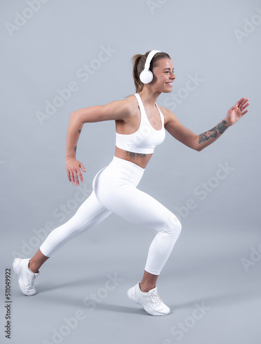 Fitness woman runner. Beautiful strong happy cheerful sports woman posing on isolated background. Happy young woman in sports clothing smiling. Muscular fitness model.
