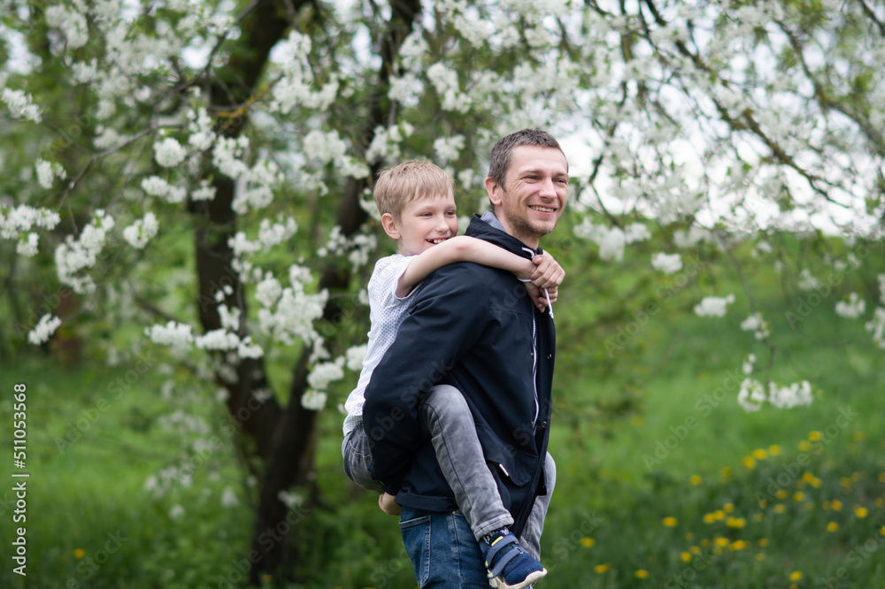 The boy is sitting on Dad's back and they are laughing The boy is sitting on Dad's back and they are laughing