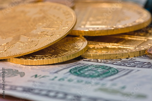 Closeup image of a loose assortment of gold coins on a US dollar backdrop.