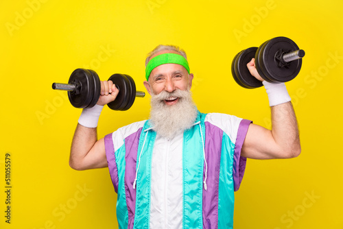Photo of excited cheerful granddad toothy smile hands hold lift dumbbells isolated on yellow color background
