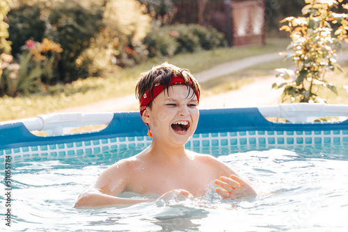 Portrait of smiling gen z Happy teen boy jumping in swimming pool at home backyard. Cute child toddler having fun enjoy summer time vacation laughing, yelling splashing water drops. Stay cooling off.