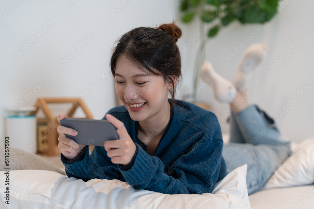 Closeup of asian woman playing online game on mobile phone on her bedroom. Closeup of asian woman playing online game on mobile phone on her bedroom.