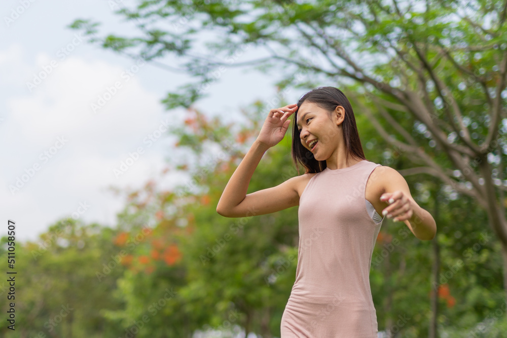 Portrait photo of a young beautiful asian female lady in pink dress embracing the breeze wind relaxingly and chillingly in a public park Portrait photo of a young beautiful asian female lady in pink dress embracing the breeze wind relaxingly and chillingly in a public park