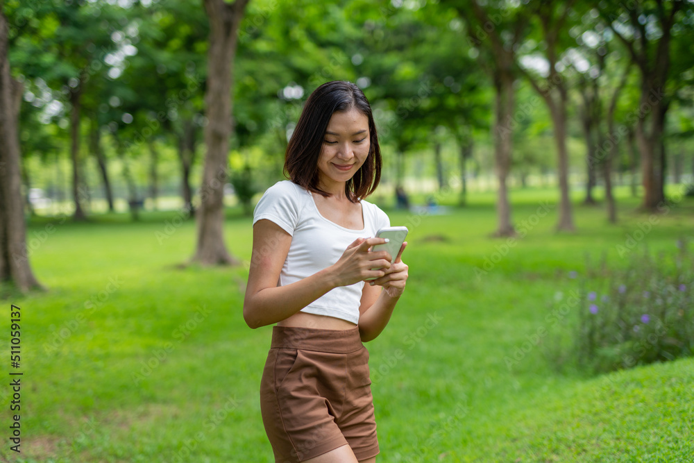 Young beautiful asian woman smiling and selfie using her phone and enjoying her free time happily in a public park Young beautiful asian woman smiling and selfie using her phone and enjoying her free time happily in a public park