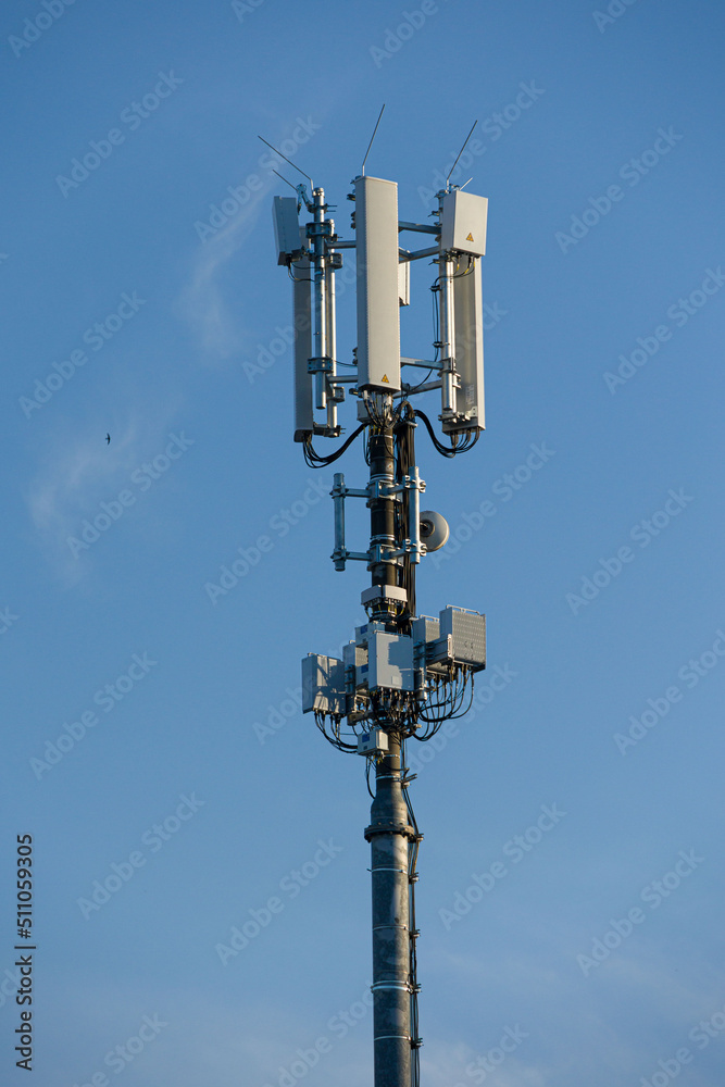an antenna mast for mobile services mounted at a roof top in front of blue sky an antenna mast for mobile services mounted at a roof top in front of blue sky