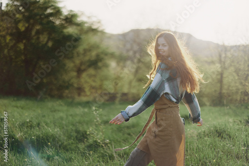 A woman running through a field on a summer day with long flowing hair in the rays of the setting sun. The concept of freedom and harmony with nature
