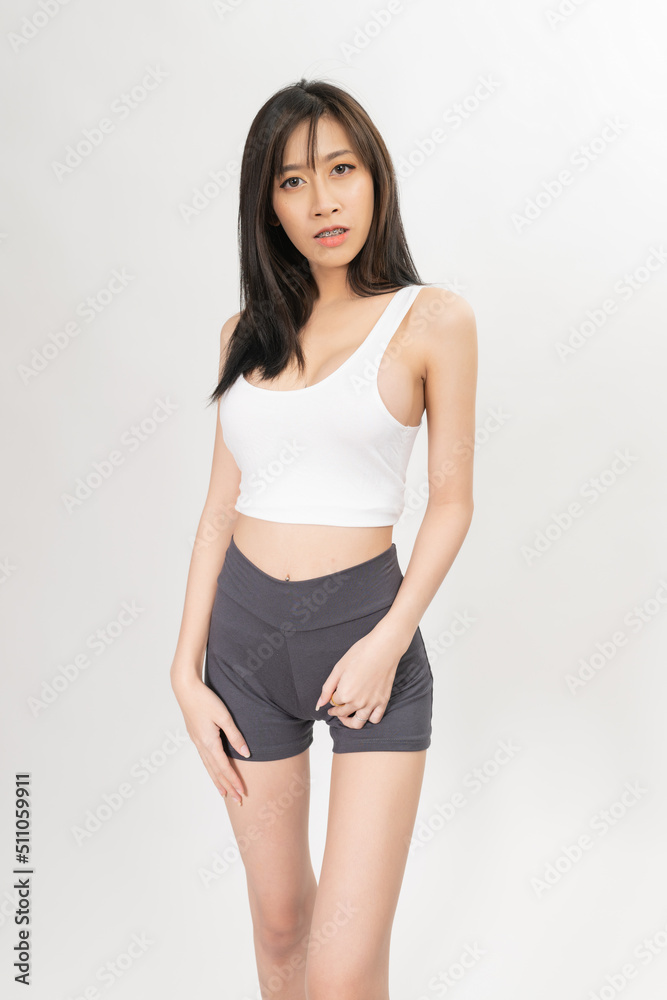 Portrait of a young and sexy beautiful asian female lady model with nice body shape wearing white tops and grey pants for indoor exercise Portrait of a young and sexy beautiful asian female lady model with nice body shape wearing white tops and grey pants for indoor exercise