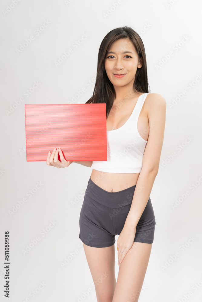 Portrait of a young and sexy beautiful asian female lady model with nice body shape wearing white tops and grey pants holding a red card board, good for promo sales ad Portrait of a young and sexy beautiful asian female lady model with nice body shape wearing white tops and grey pants holding a red card board, good for promo sales ad