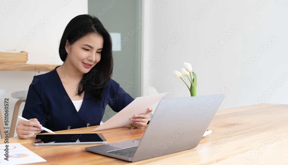 Young asian businesswoman works on tablet with laptop at the office. Young asian businesswoman works on tablet with laptop at the office.