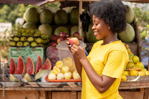 african woman holding an apple in a market
