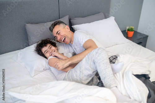 Father and son talking in bed in the morning and looking cheerful