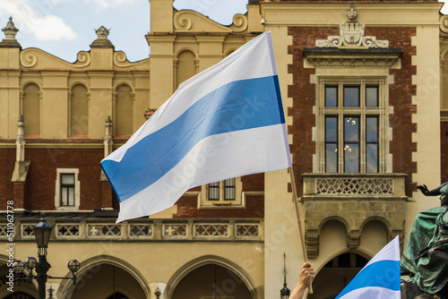 White-blue-white flag - a symbol of opposition to the 2022 Russian invasion of Ukraine, the Russian anti-war flag on a sunny day against the background of houses and a cloudy sky photo