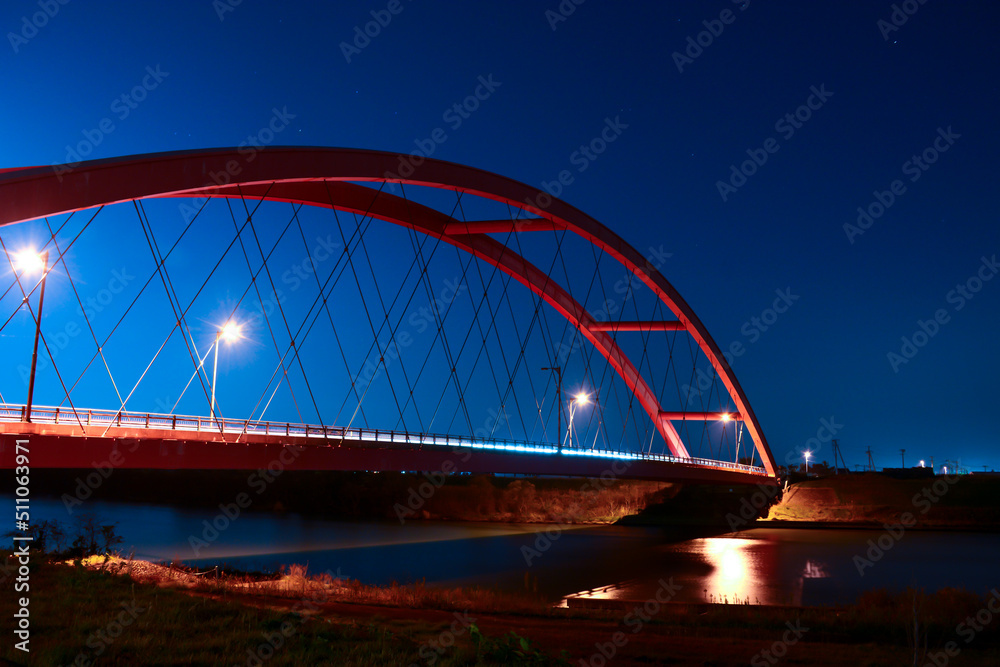 夜の闇に浮かぶ赤い橋と光るライト