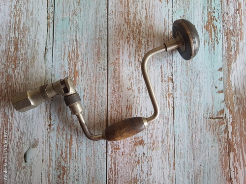 Old hand drill. Hand drill. Ancient hand tool. Construction work and repairs. On an old wooden table, top view. photo