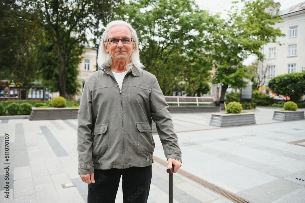 Elderly man walks with a cane in a city spring park. Elderly man walks with a cane in a city spring park.