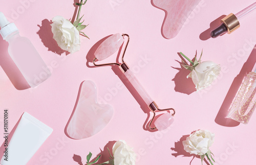 Wallpaper Mural Creative composition made of face roller, gua sha massager, bottle of cosmetic serum on pink pastel sunlit background with white rose buds and shadows. Natural treatment concept. Top view. Flat lay Torontodigital.ca