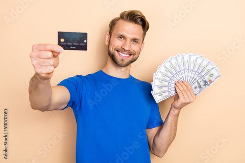 Photo of young cheerful man hold bank card income profit investment isolated over beige color background